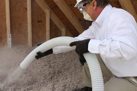 man spraying insulation in an attic