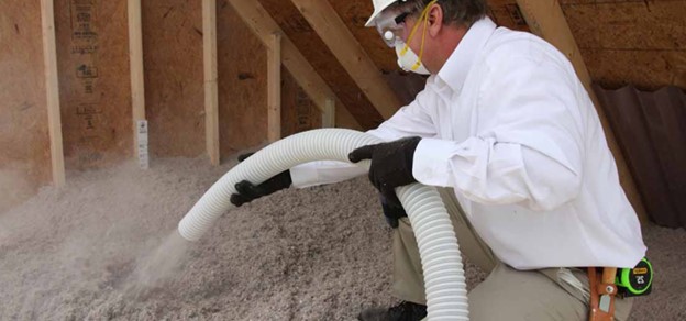 man spraying insulation into an attic.